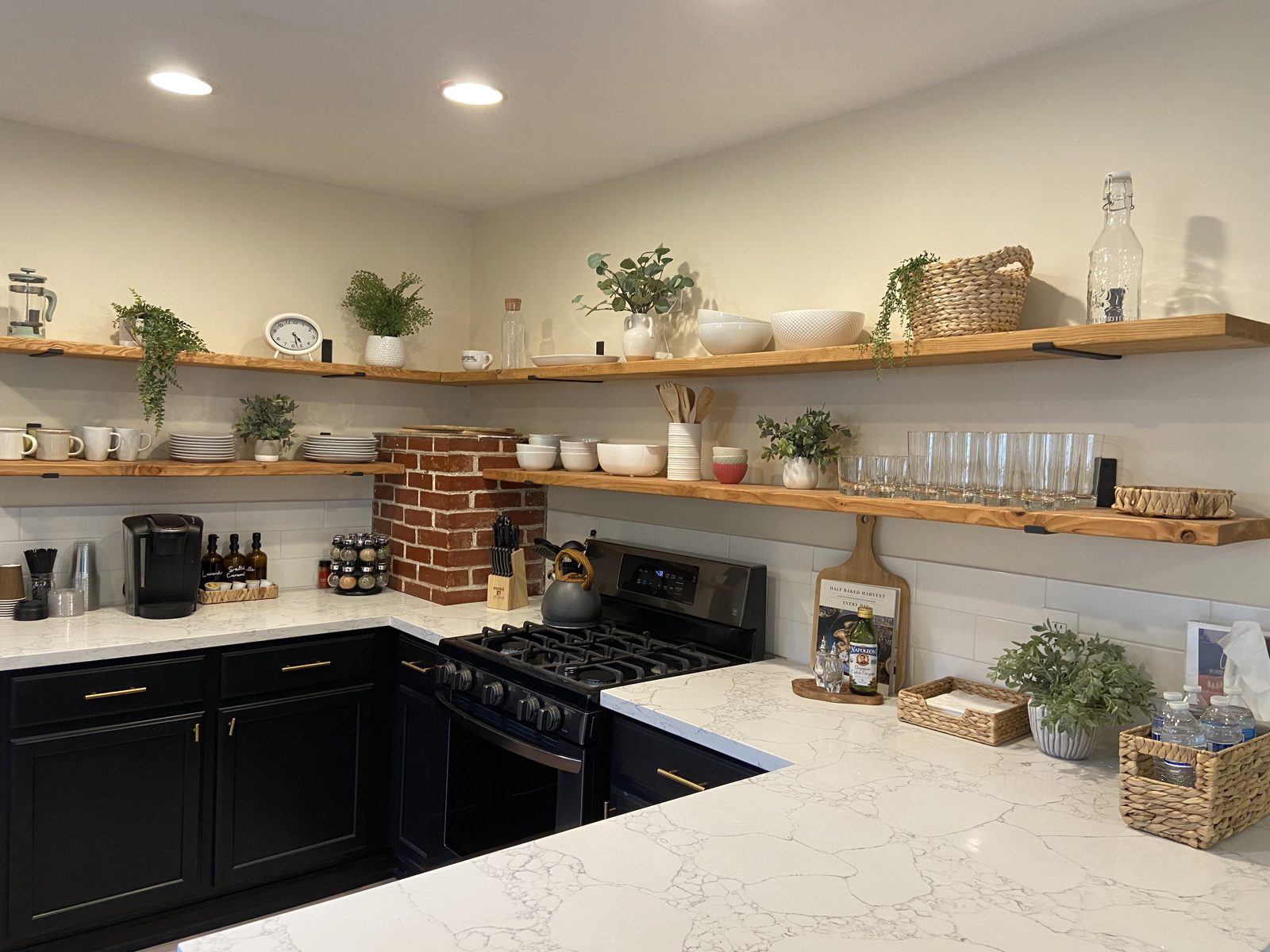 Finished kitchen with black cabinets, quartz counters and exposed brick